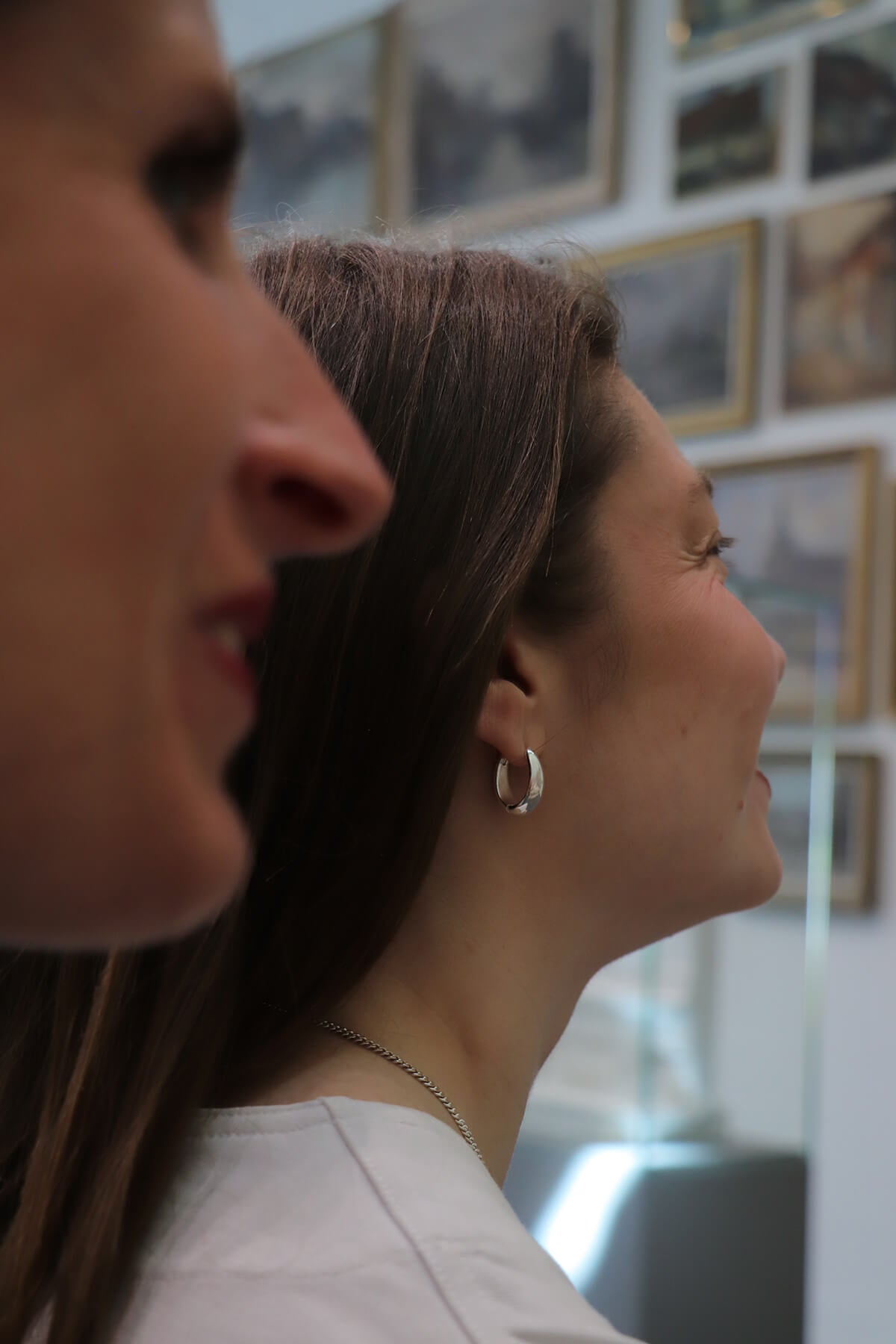Magaly wearing Splash hoops at La Piscine Musée Roubaix with gallery paintings in the background.