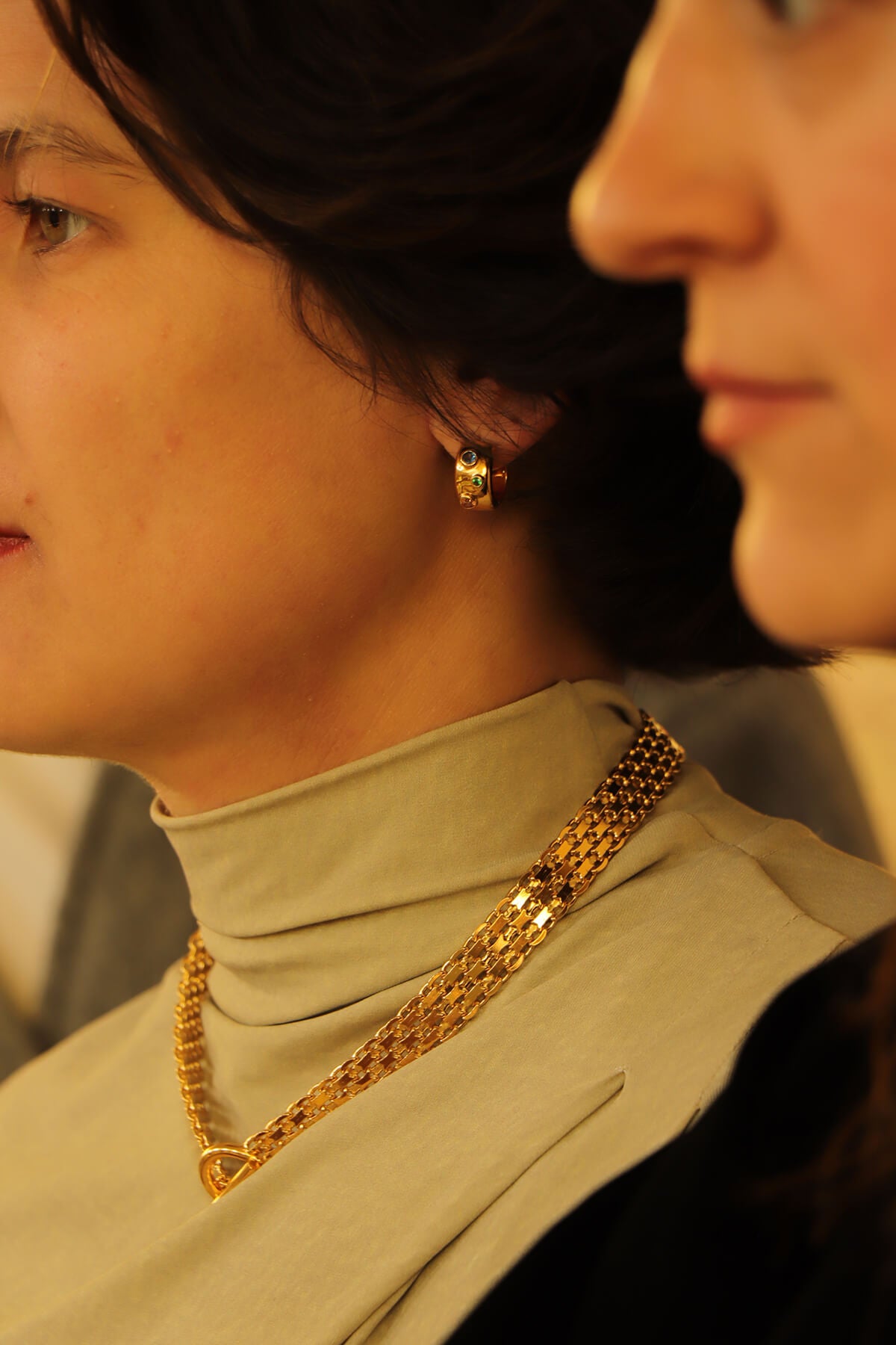 Hannah wearing Drip necklace and Spill hoops in profile beside Saskia at La Piscine Musée Roubaix.