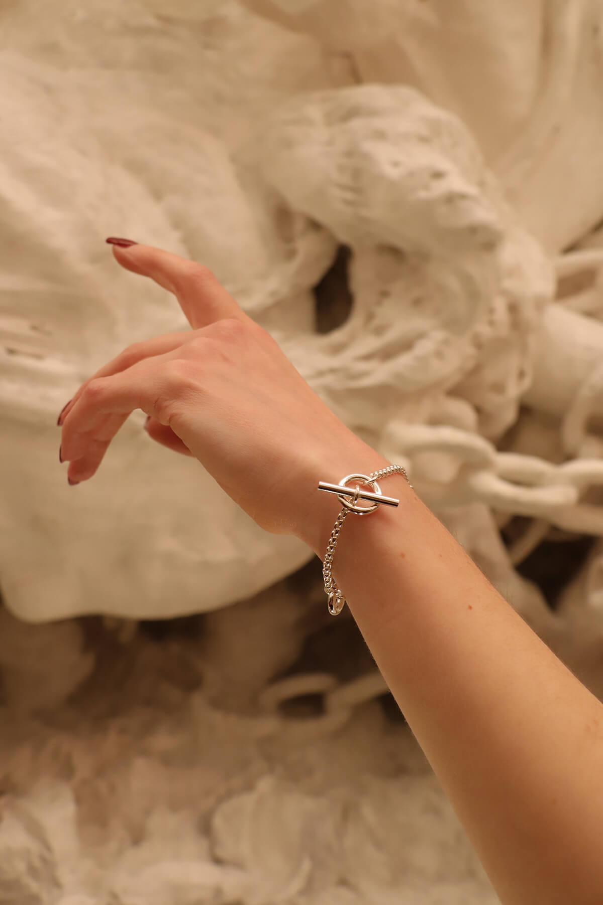 Splash bracelet worn on the wrist in front of a marble sculpture at La Piscine Musée Roubaix.