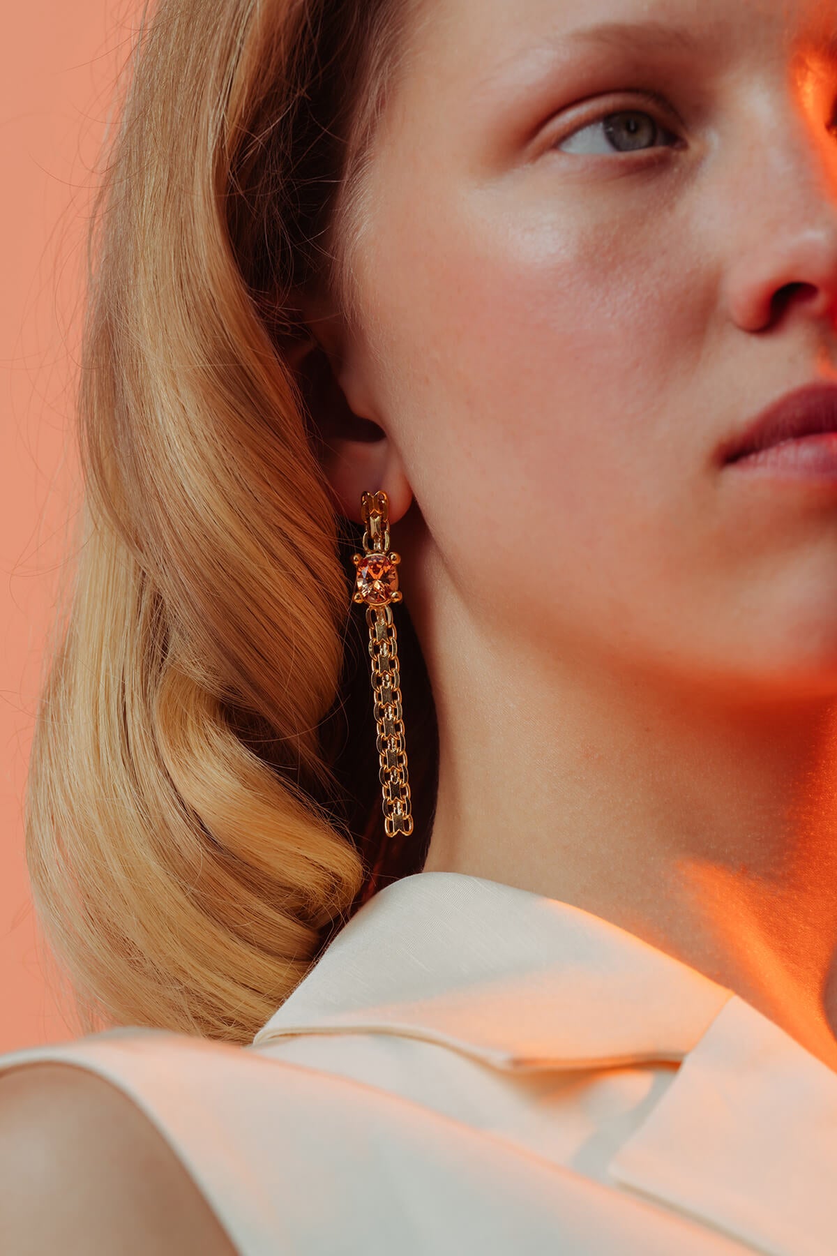 Drip earrings with an oval orange cubic zirconia in a four-prong setting suspended from articulated chain links.