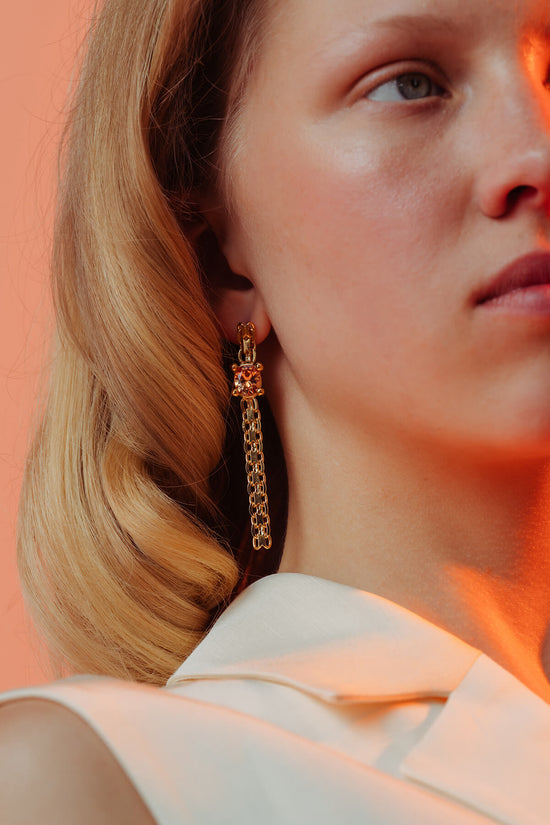 Drip earrings with an oval orange cubic zirconia in a four-prong setting suspended from articulated chain links.