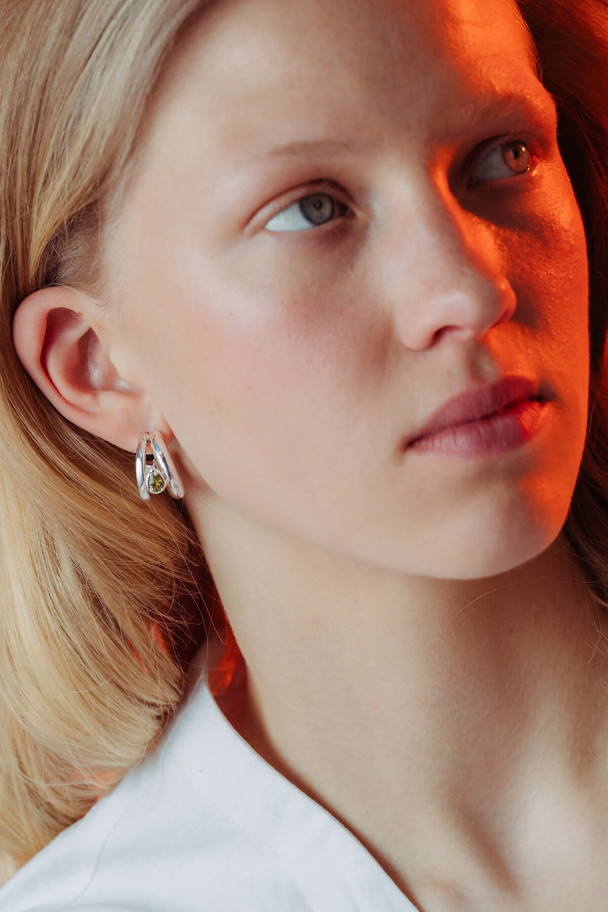 Drop hoops with cubic zirconia in silver with contrasting hoop shapes surrounding a green pear-shaped cubic zirconia.