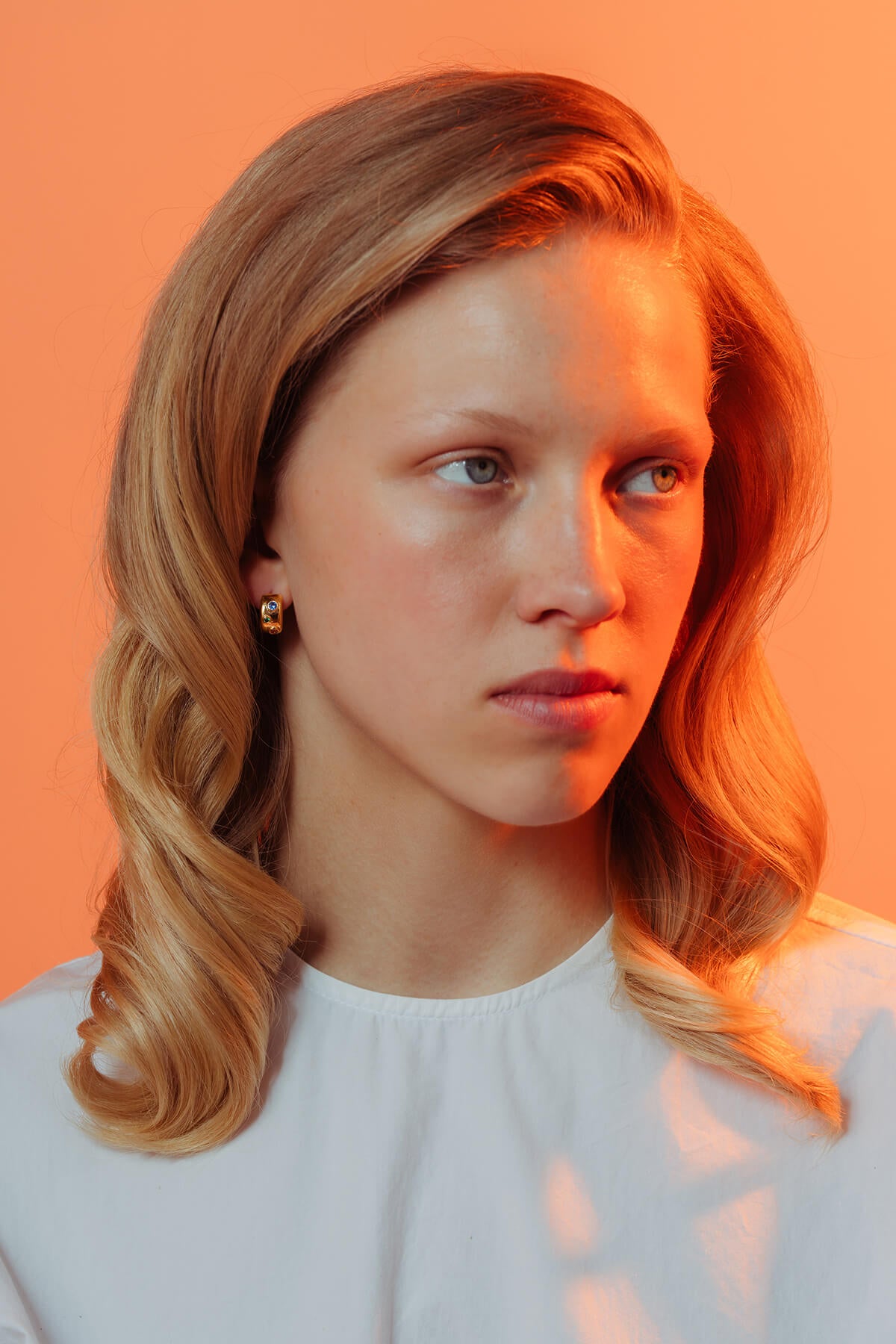 Spill hoops with cubic zirconia in a gold-plated finish featuring rounded hoops set with blue, green and orange stones.