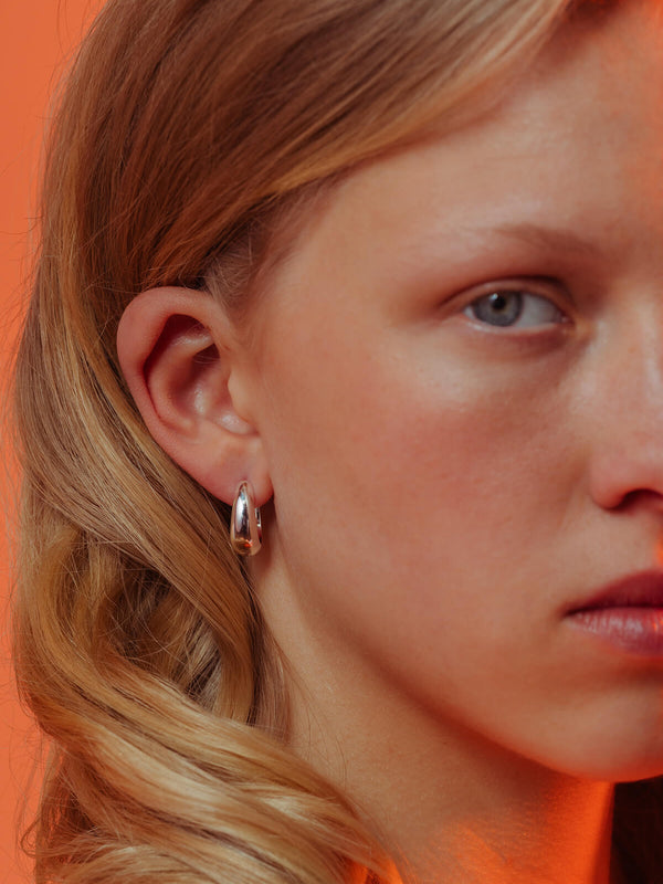 Splash hoops in silver with rounded droplet-inspired hoops shown worn in the ear.