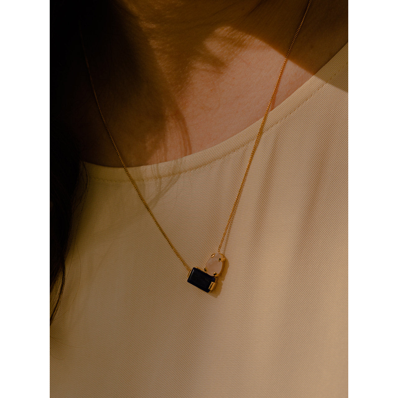 This necklace showcases a composition of an emerald-cut sodalite and a drop-shaped pink quartz, delicately suspended on a minimalistic gourmet chain.