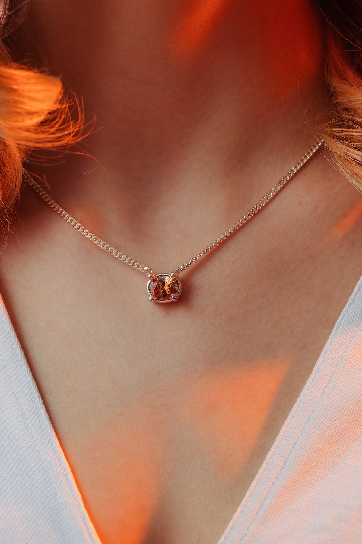 Drip necklace with cubic zirconia with an oval orange cubic zirconia in an oversized four-prong setting on a silver chain.