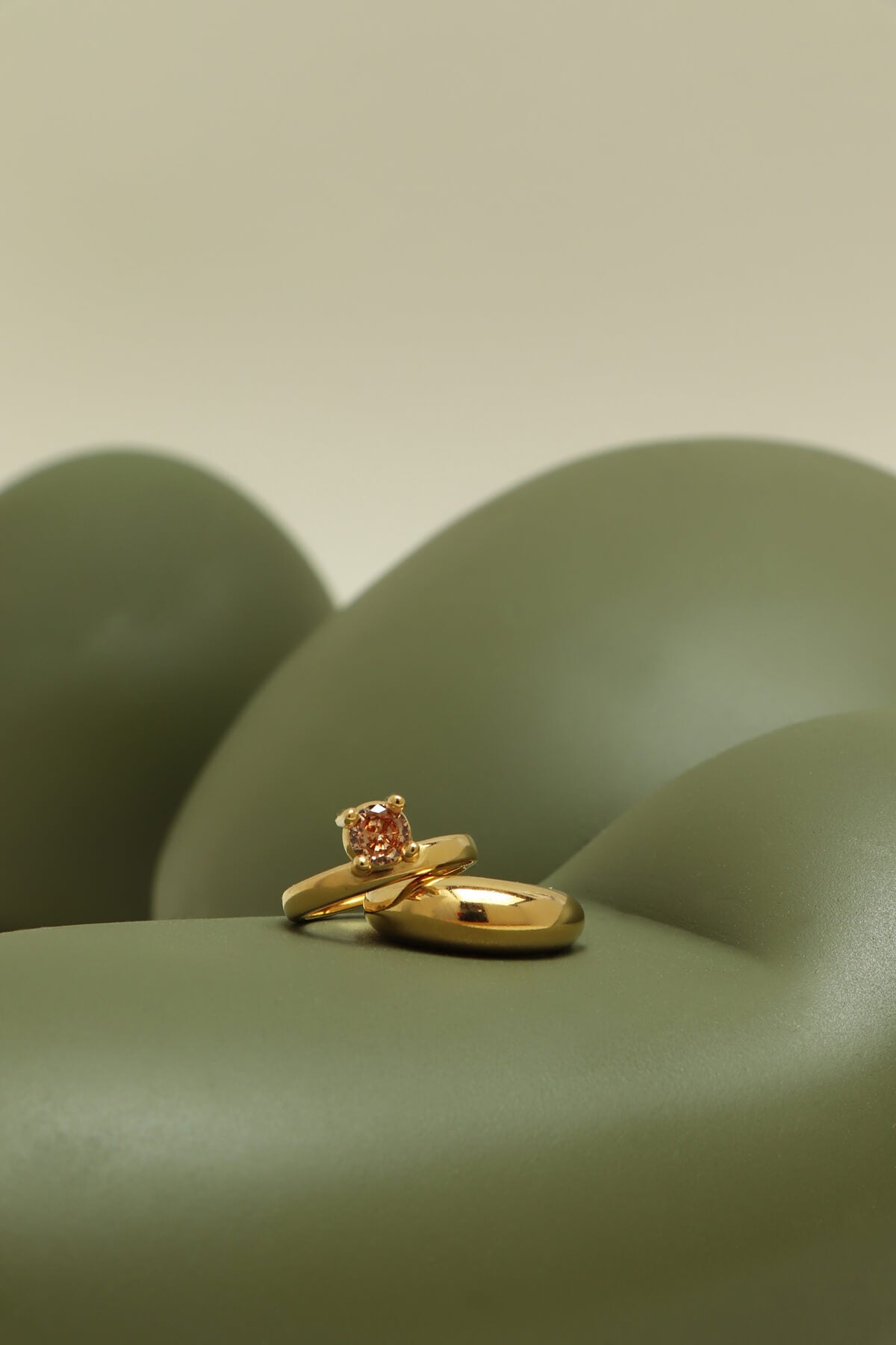 Drip ring with cubic zirconia showcasing an orange round stone in an oversized four-prong setting on a flowing green sculptural form.