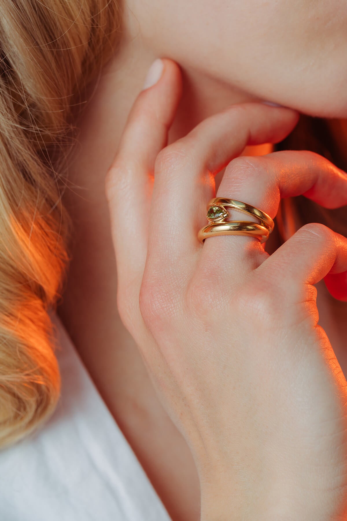 Drop ring with cubic zirconia and contrasting bands featuring a green drop-shaped cubic zirconia, worn on the finger.