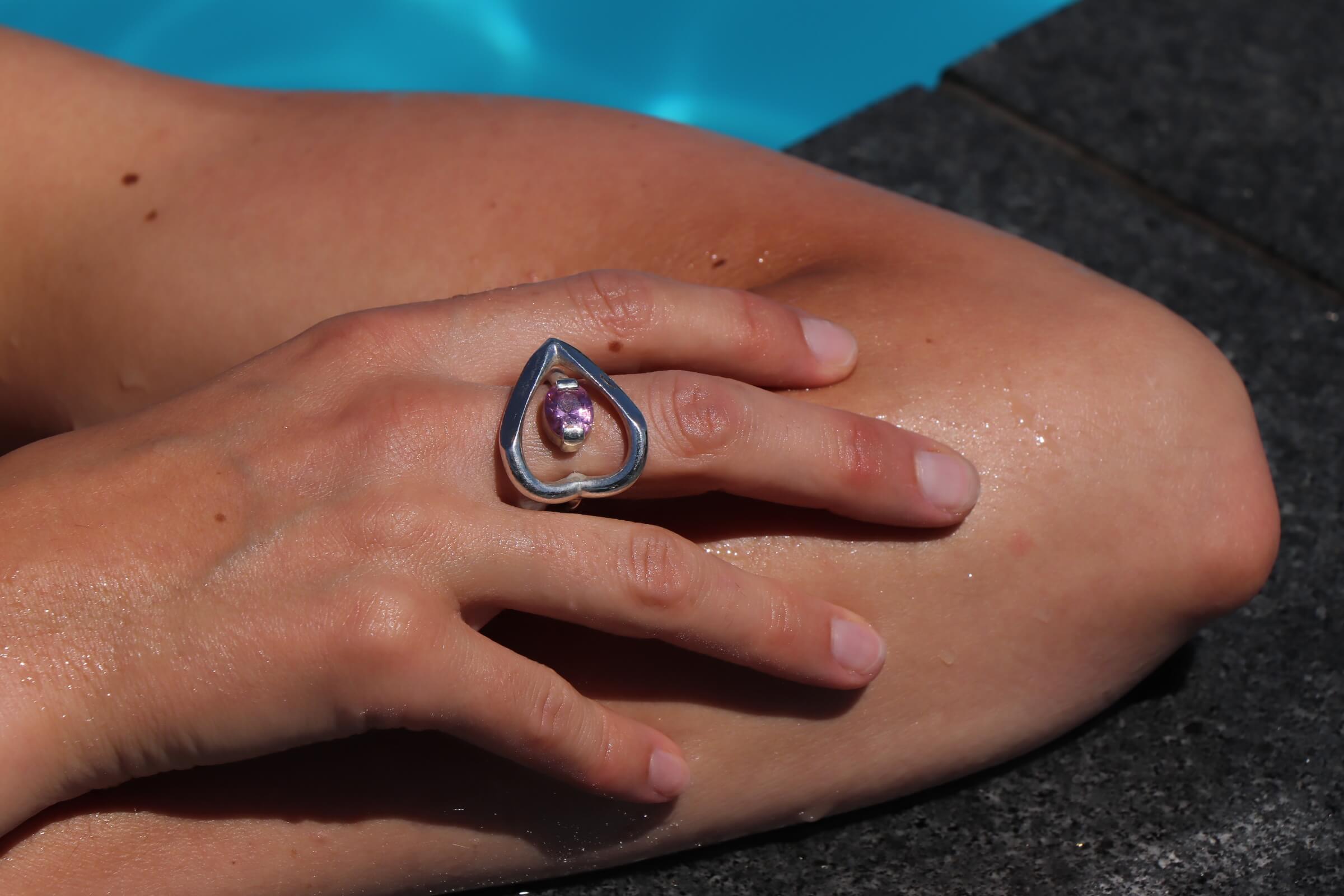 Pulse ring with cubic zirconia in silver featuring a pink oval-cut cubic zirconia worn on a hand in a relaxed poolside setting.