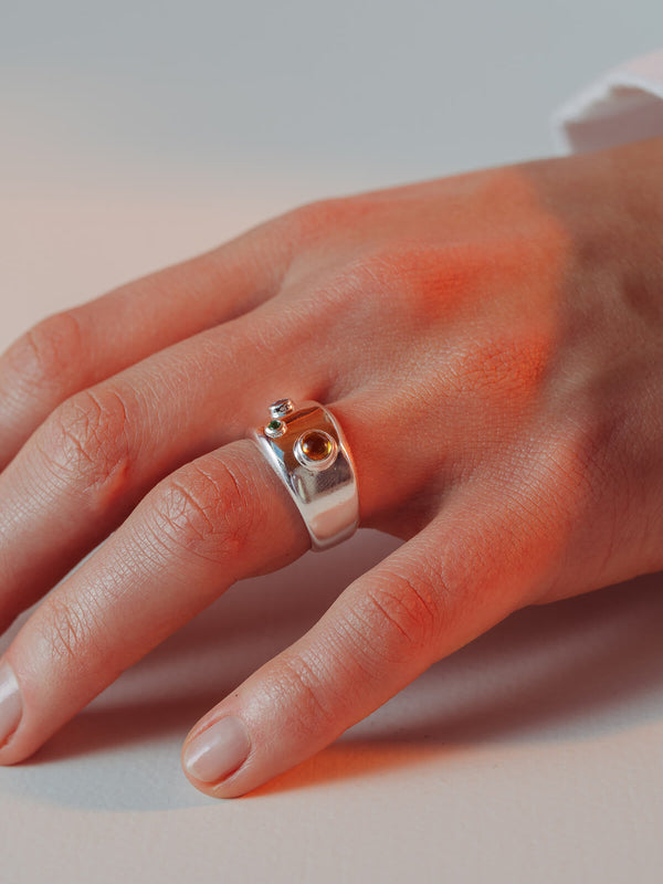 Spill ring with cubic zirconia worn on the hand showing three bezel-set blue, green and orange cubic zirconia stones.