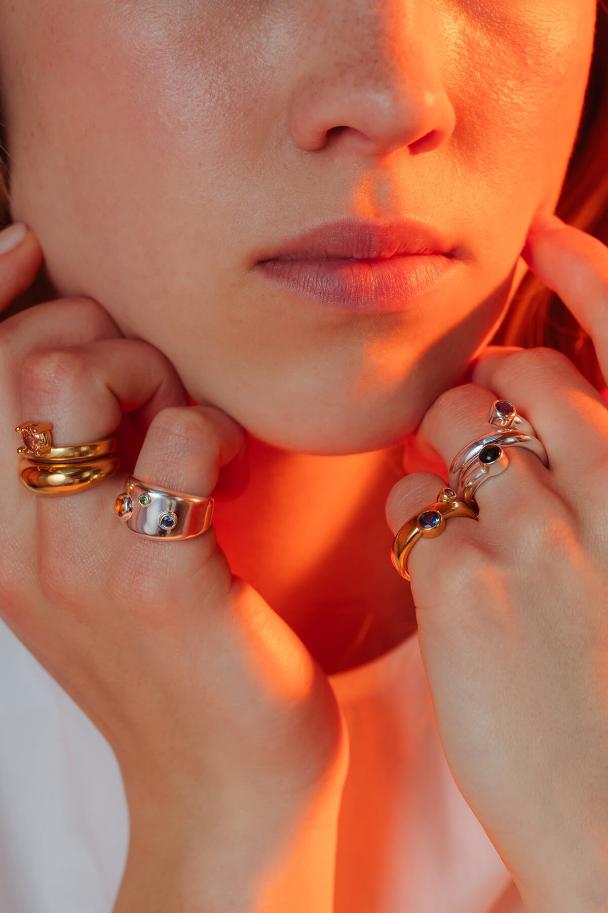 Drip drop rings styled on both hands with silver and gold rings featuring blue, green and orange cubic zirconia.