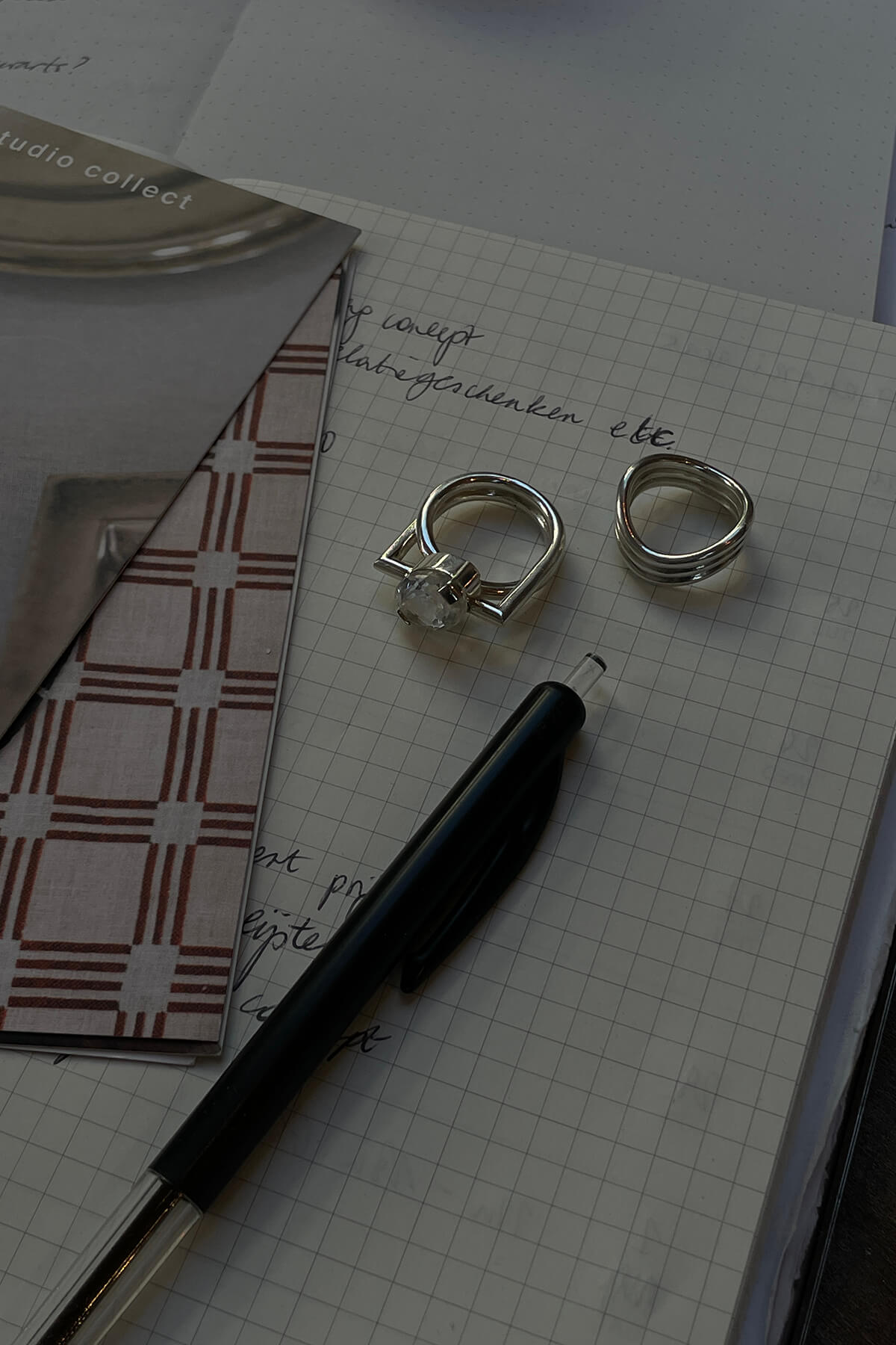 Image of the Studio Collect Echo Ring with crystal quartz presented on a notebook next to a pen.