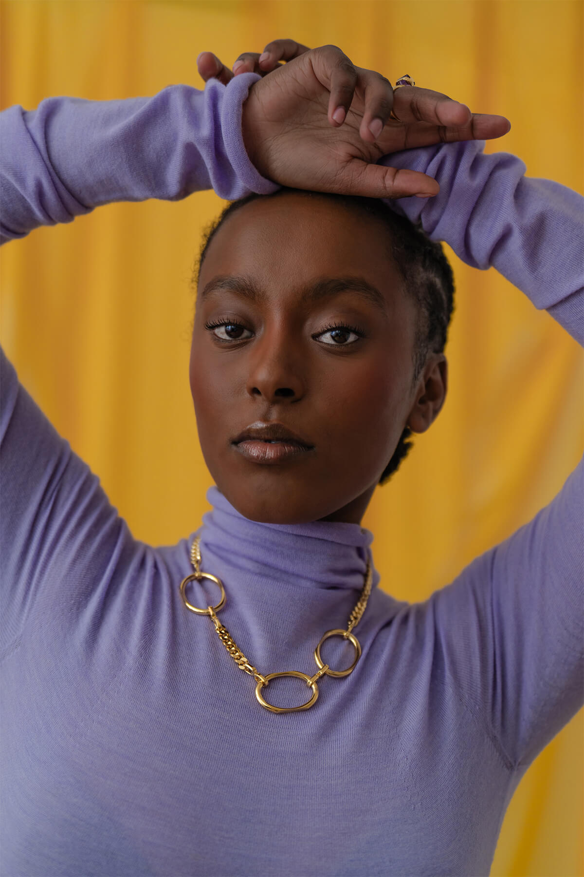 Meseret pairs our Facet Necklace with a purple turtleneck- a bold statement piece that elevates any wardrobe.