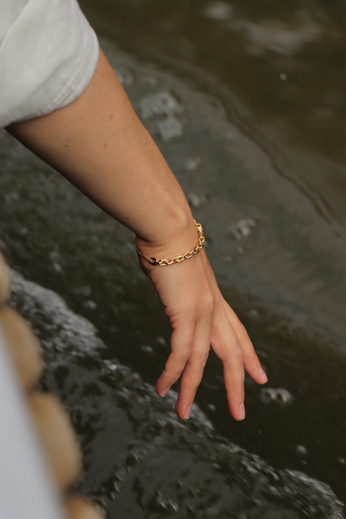 Studio Collect Cordy bracelet worn by Saskia during a boat trip, where she lets her hand flow through the water.
