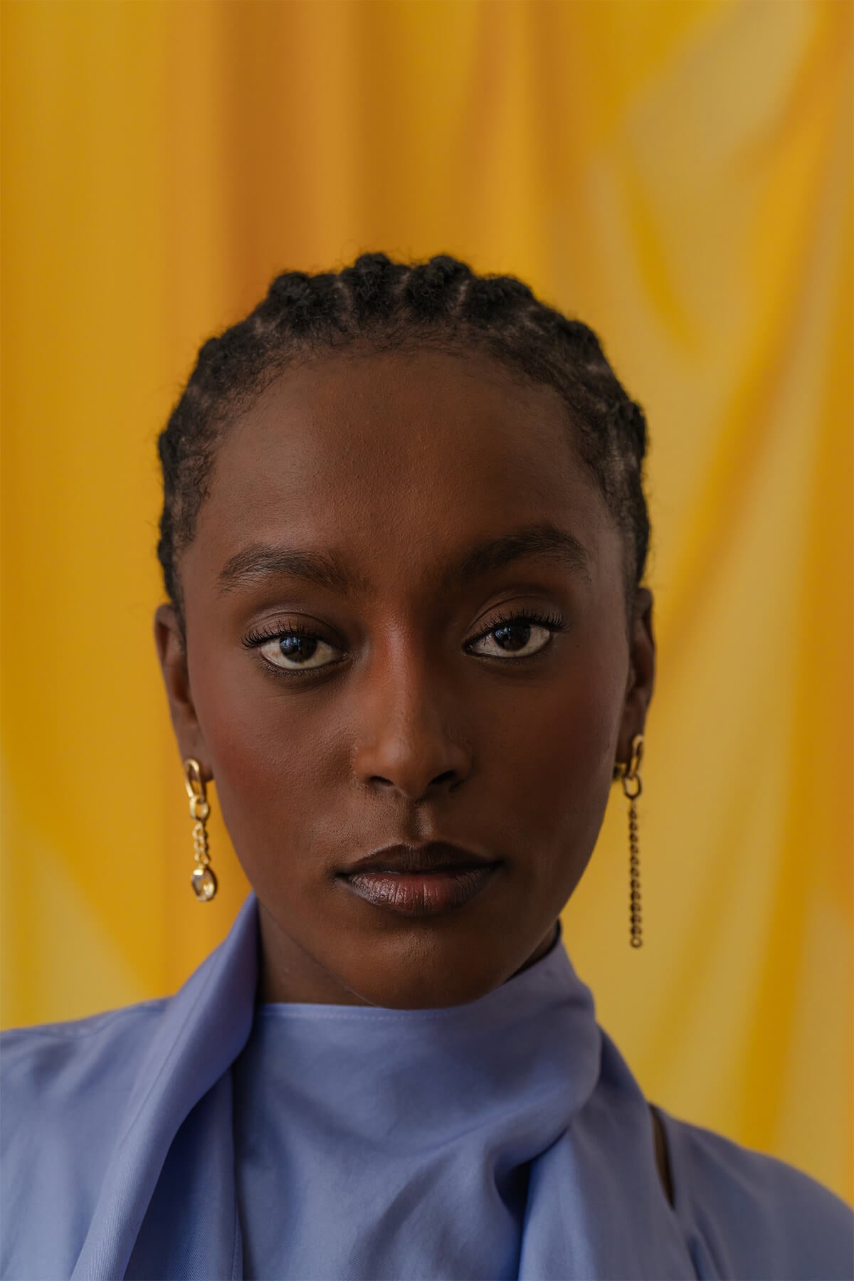 Meseret wearing the Ray Earrings – an asymmetric pair with bold chain drops, oval studs, and a touch of citrine for warmth.
